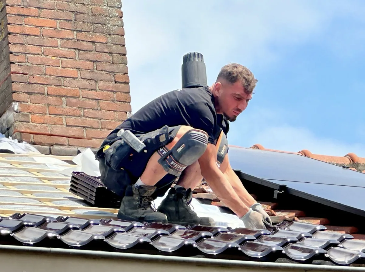 Dakdekker legt nieuwe geglazuurde dakpannen naast een dakraam
